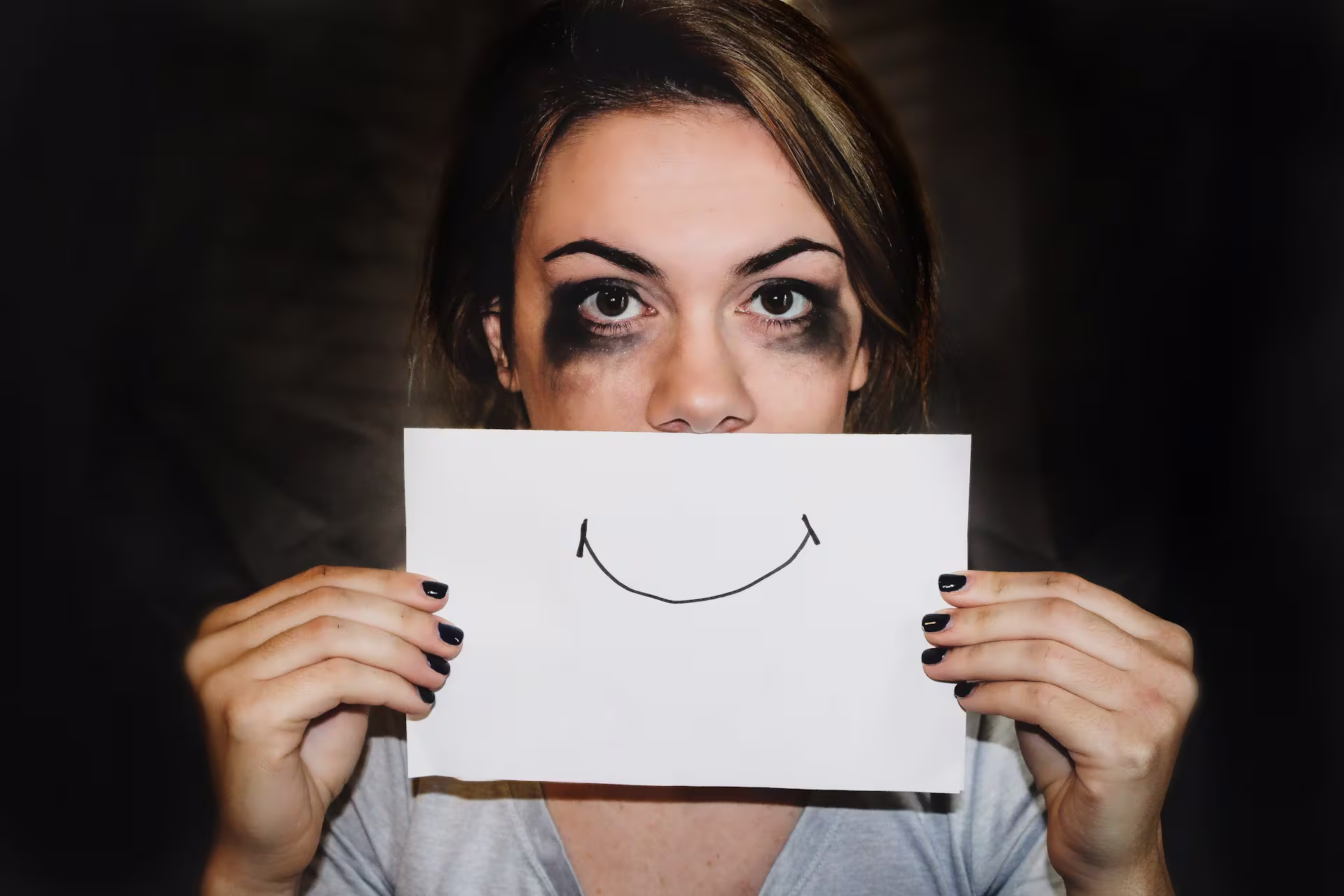 Mujer sosteniendo papel con dibujo sonrisa